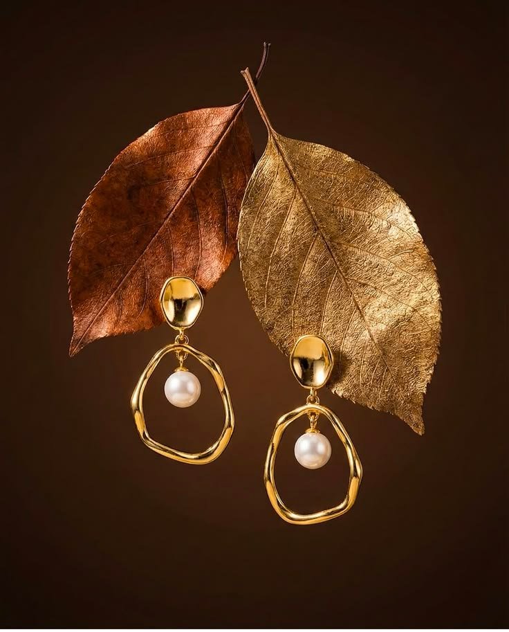 Elegant gold-tone hoop earrings with decorative detailing on a dark background